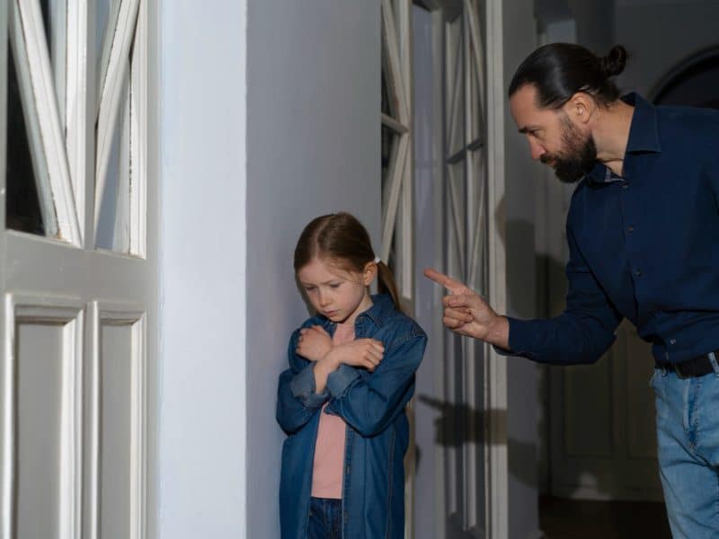 Pai narcisista apontando o dedo e intimidando filha criança